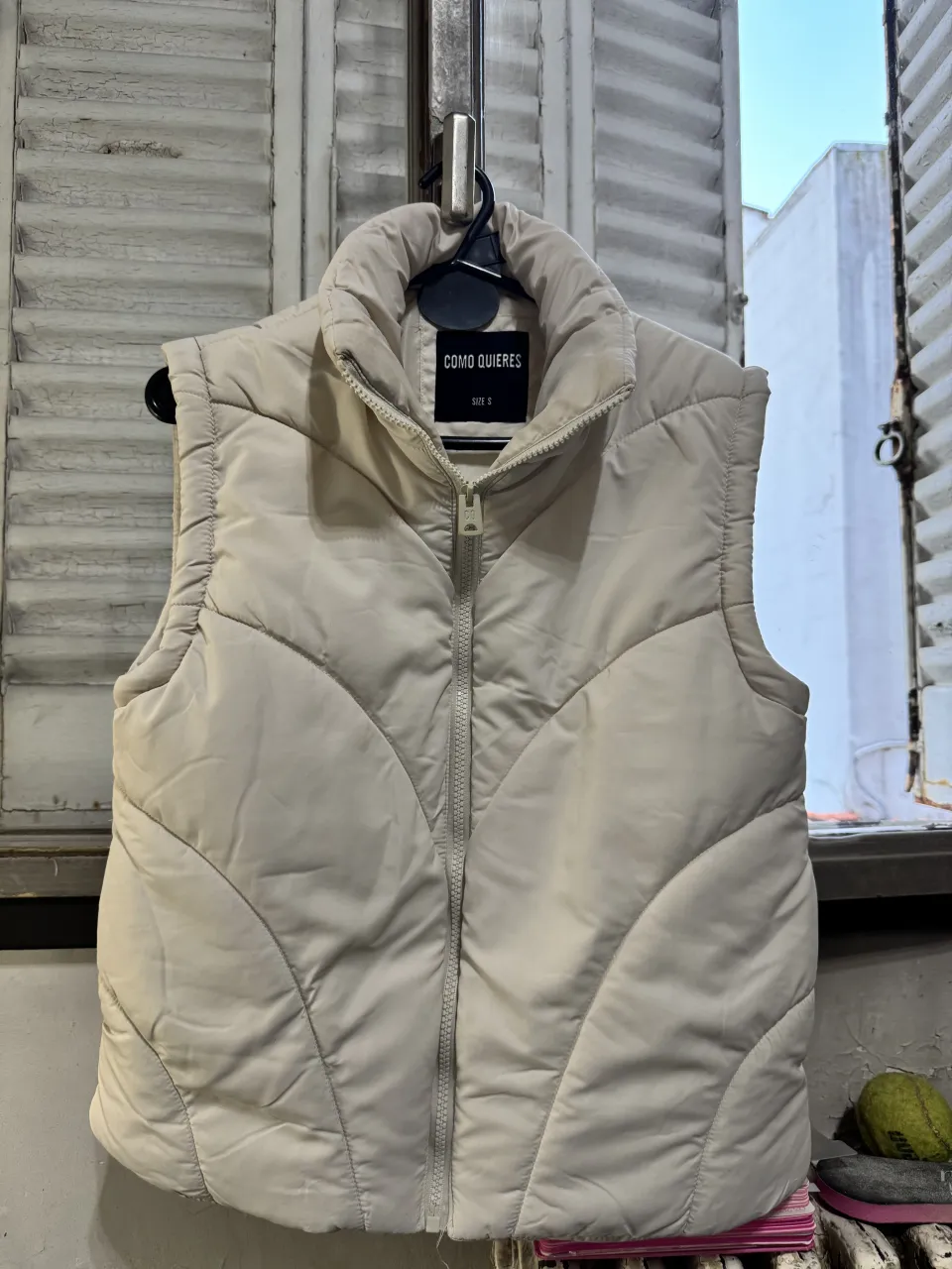 Chaleco acolchado color crudo con cuello alto y cierre al frente. Posee bolsillos laterales con cierre.