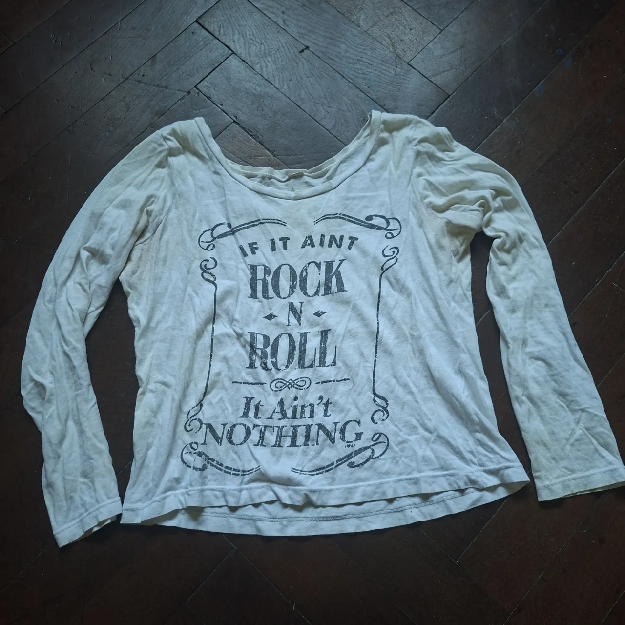Remera blanca/beige de manga larga con estampa "IF IT AIN'T ROCK 'N' ROLL IT AIN'T NOTHING" en negro.