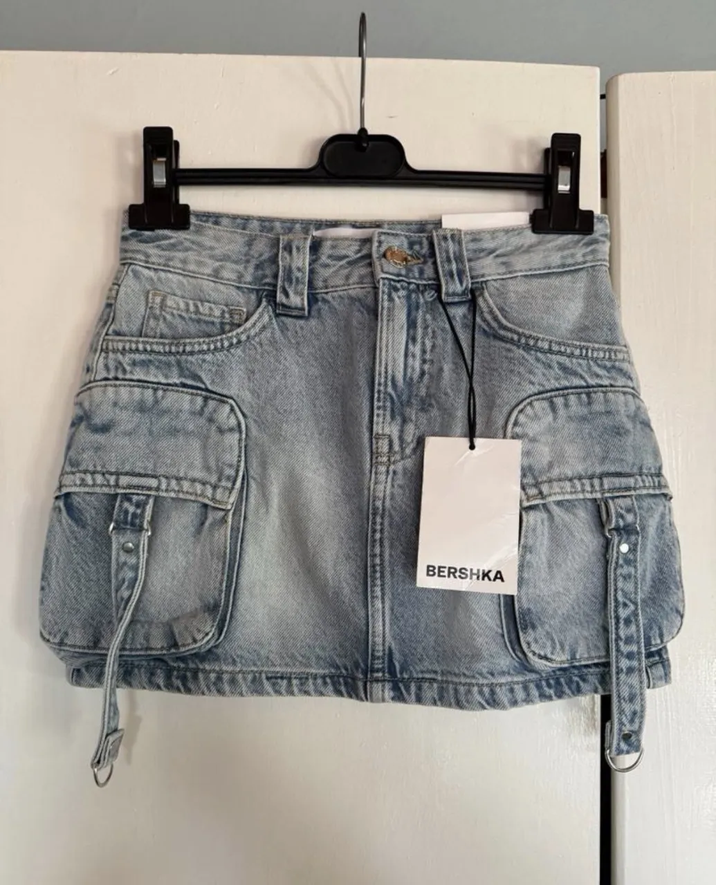 Pollera de jean tiro alto con bolsillos cargo y detalles de tiras con hebillas. Lavado celeste.