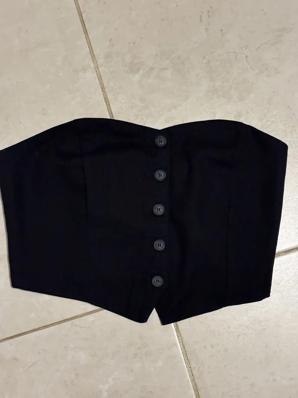 Top negro strapless con botones al frente. Ideal para looks cancheros y de fiesta.