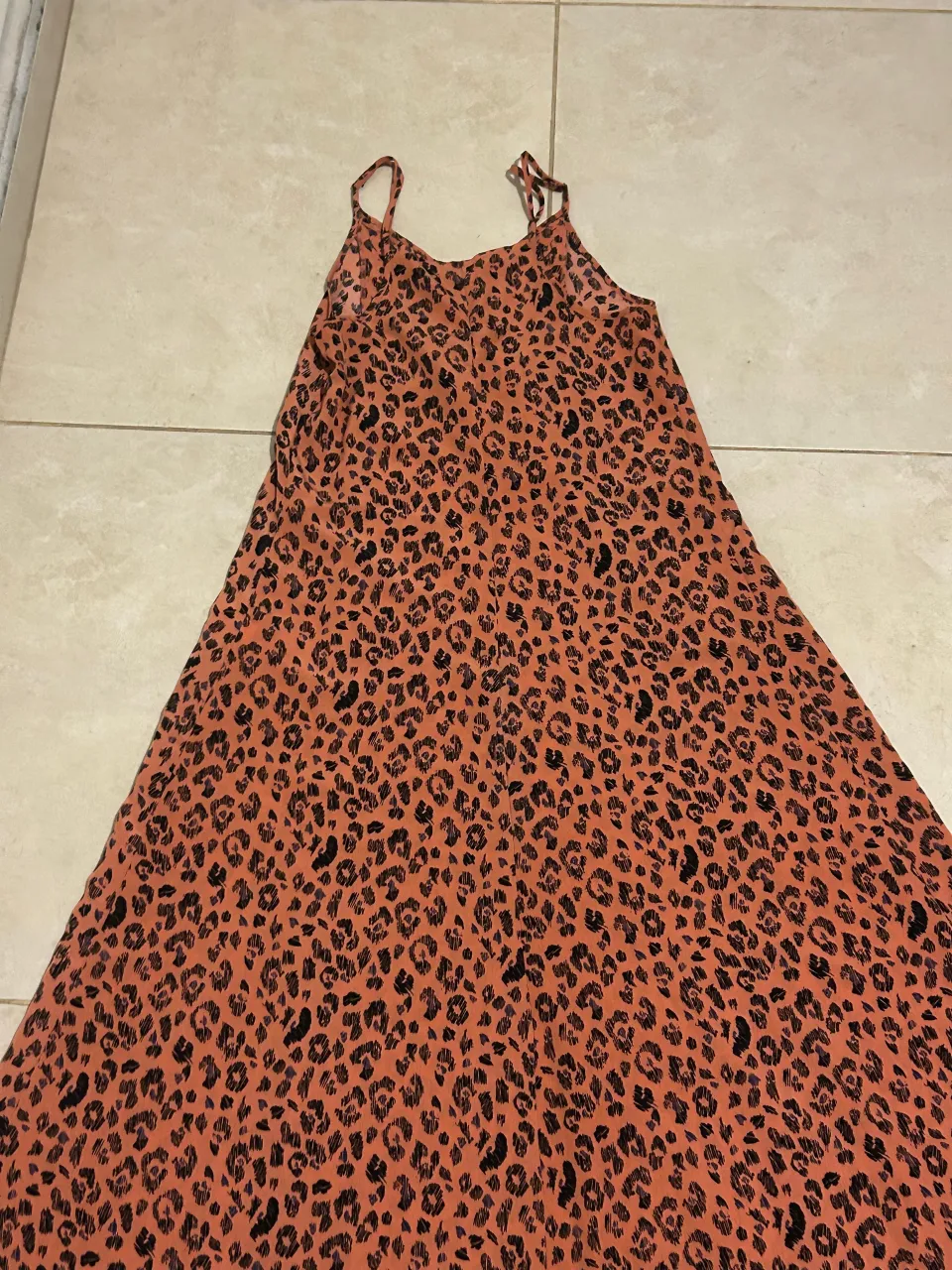 Vestido corto con estampa animal print en tonos naranjas y negros. Posee detalles de lentejuelas plateadas en el escote y breteles finos. Ideal para un look canchero y divertido.