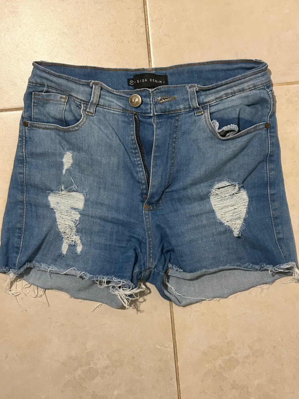 Shorts de jean tiro alto, con roturas y detalles desflecados en el ruedo. Un básico súper canchero para armar looks de verano.