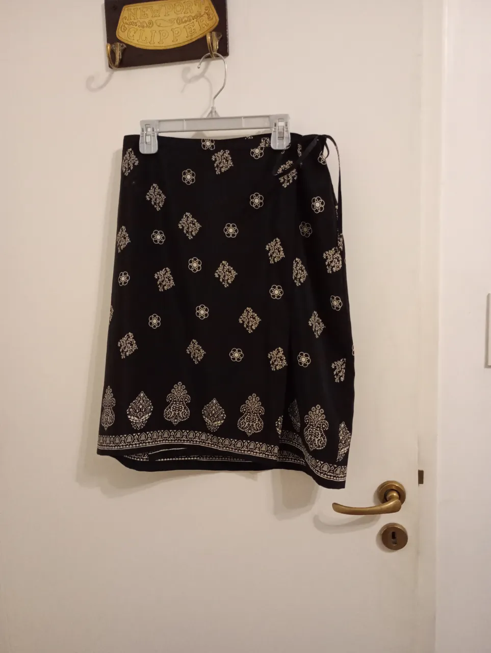 Pollera corta tipo pareo negra con estampa de motivos florales y geométricos en blanco. Posee un lazo para atar en la cintura. Talle 4. Se ajusta casi a cualquier cuerpo. Marca Normandie. Como nueva.
