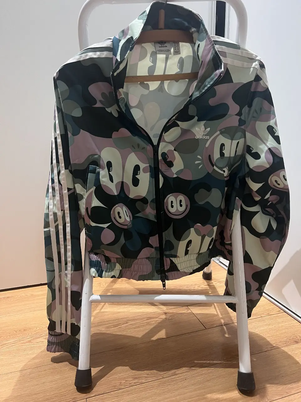 Campera deportiva Adidas con estampado de personajes de dibujos animados. Ideal para un look casual y moderno. Con cierre y detalles de las tres tiras clásicas de la marca.