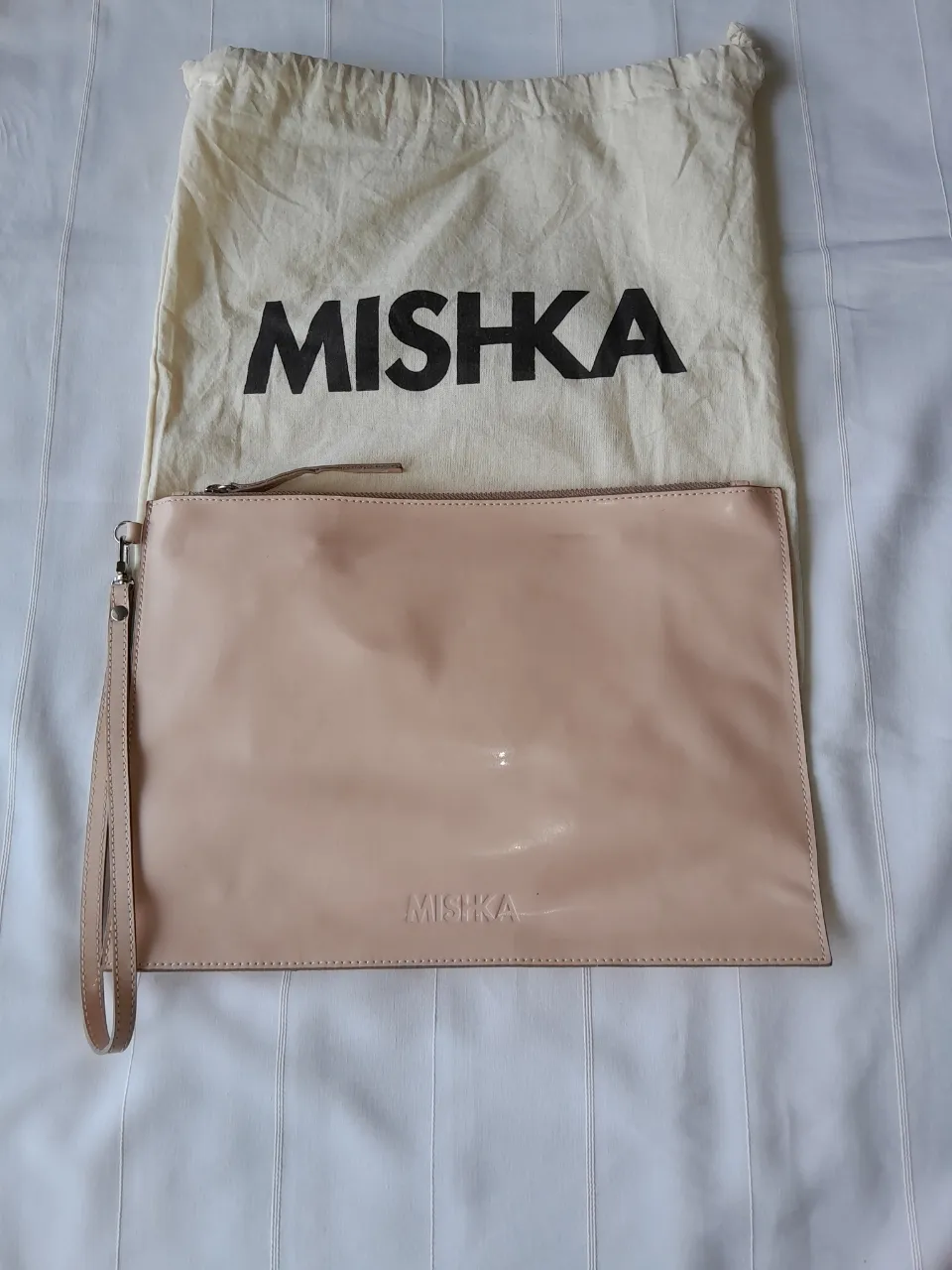 Clutch color nude con correa de mano. Incluye bolsa de tela para guardarlo.