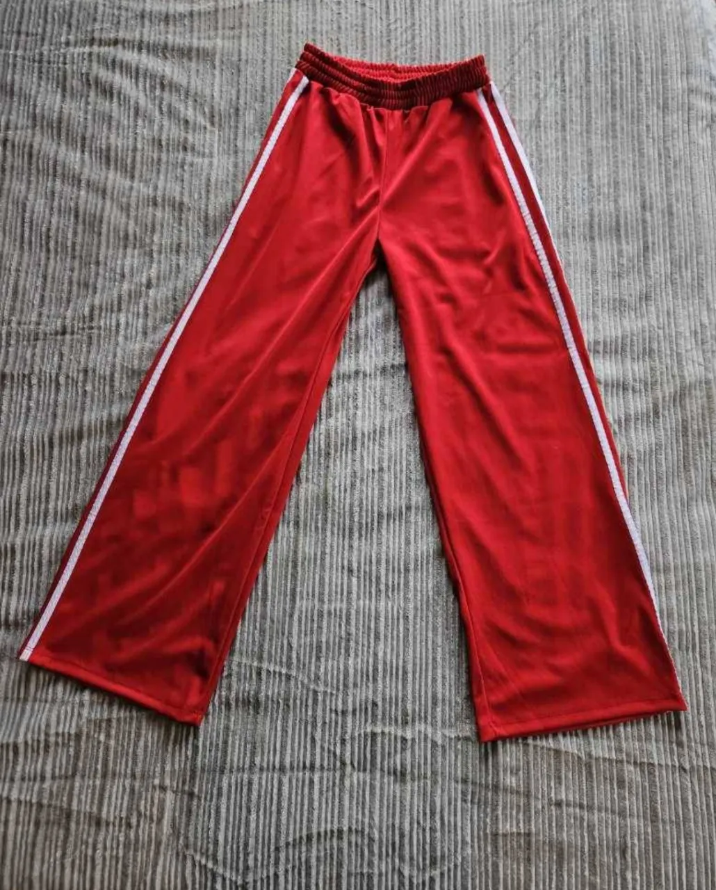 Pantalón palazo deportivo rojo con franjas blancas laterales y cintura elastizada.