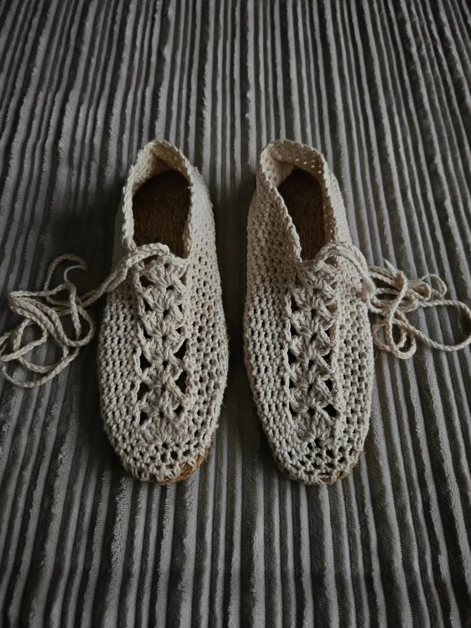 Zapatillas tejidas de crochet color crudo con cordones finos. La suela es de material rústico entrelazado.