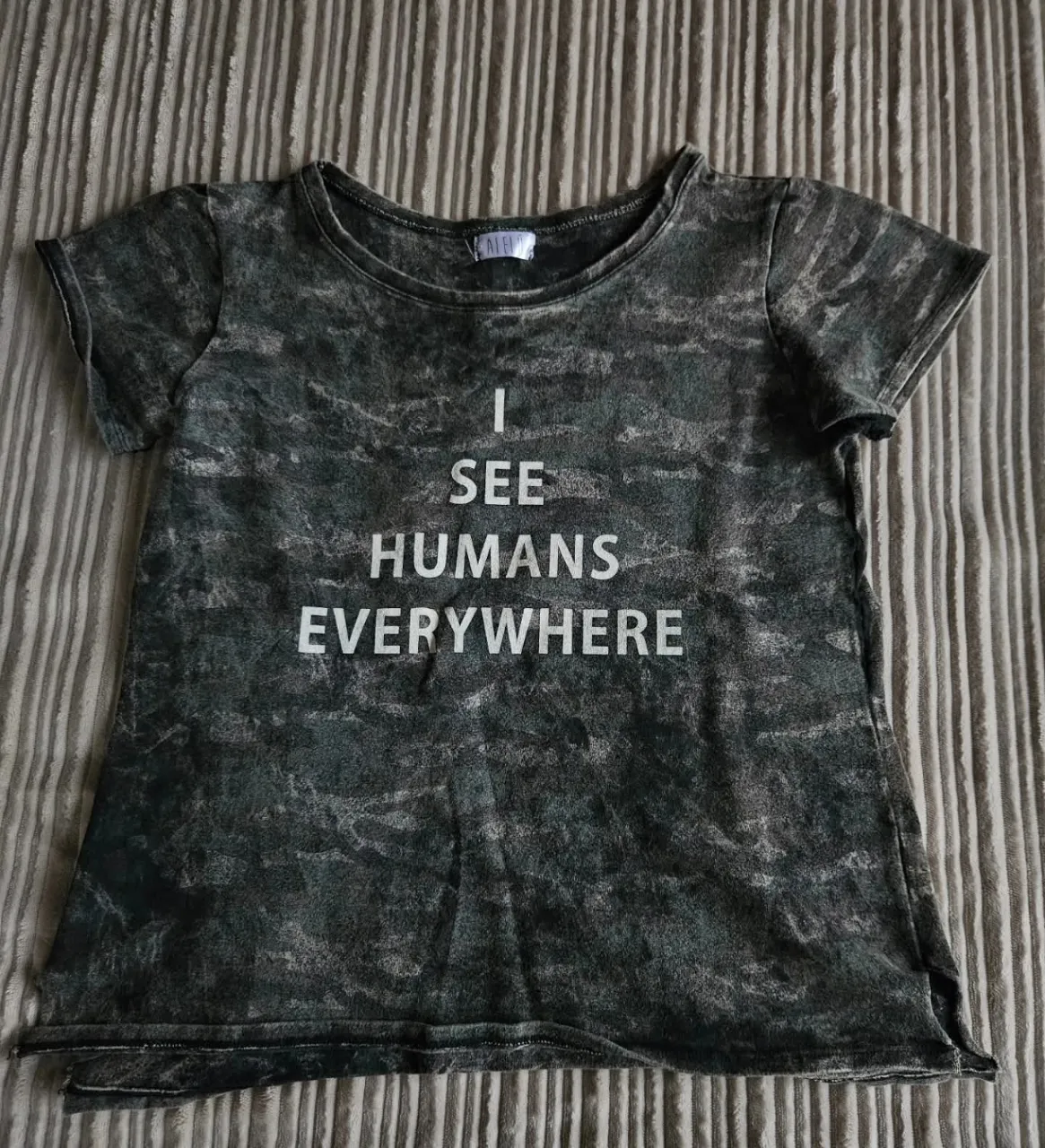 Remera gris con estampado "I SEE HUMANS EVERYWHERE". Tiene tajos debajo de los brazosby en las puntas inferiores